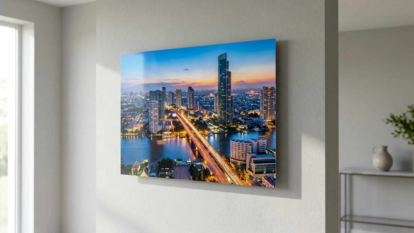 A metal print of a city skyline at blue hour with lit highways, floating off a pale grey wall on its hidden mount