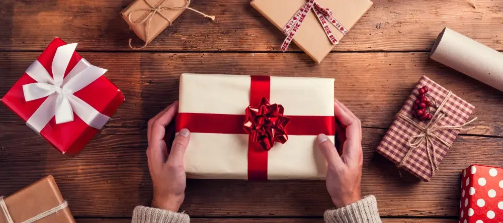 How much to spend on Christmas gifts per person: a person wrapping gifts for Christmas