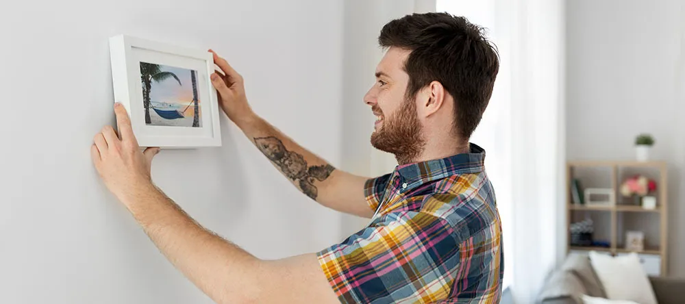 How to Hang Pictures Without Nails. Woman marking wall with pencil.