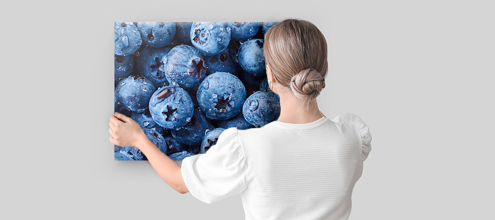 Canvas prints for the kitchen: a woman hanging a canvas print on the wall