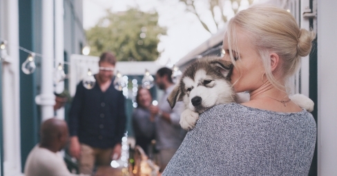 Happy dog owner holding puppy outdoors on National Puppy Day