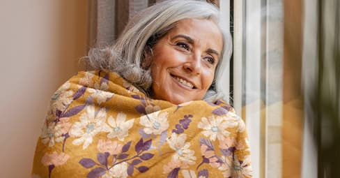 Personalized blankets for grandma: a middle-aged woman cuddling in a printed blanket